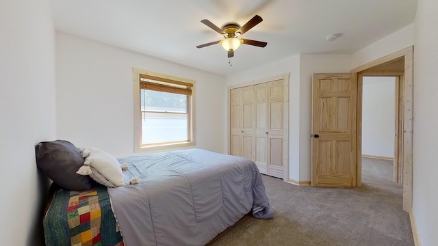 bedroom with ceiling fan, light colored carpet, and a closet