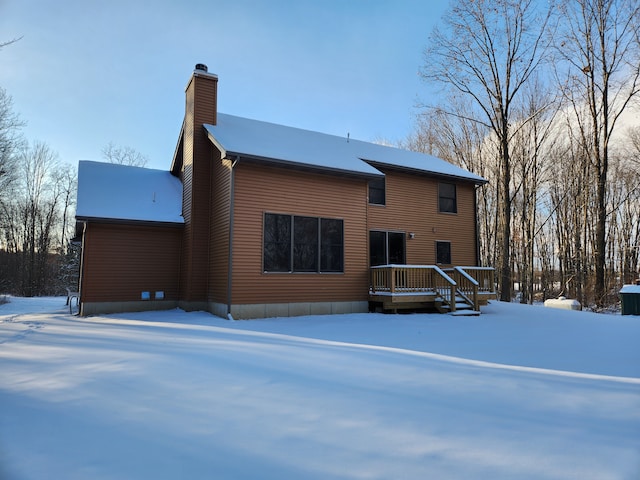 snow covered house with a wooden deck