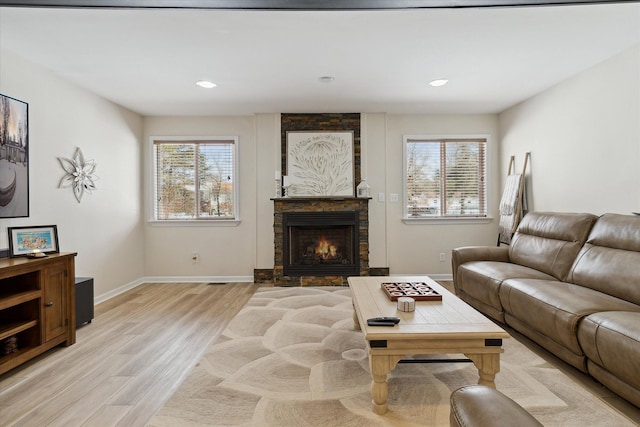 living room featuring a healthy amount of sunlight, a fireplace, and light hardwood / wood-style flooring