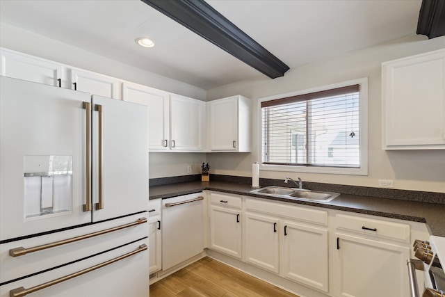 kitchen featuring sink, white cabinetry, light hardwood / wood-style flooring, beamed ceiling, and white appliances