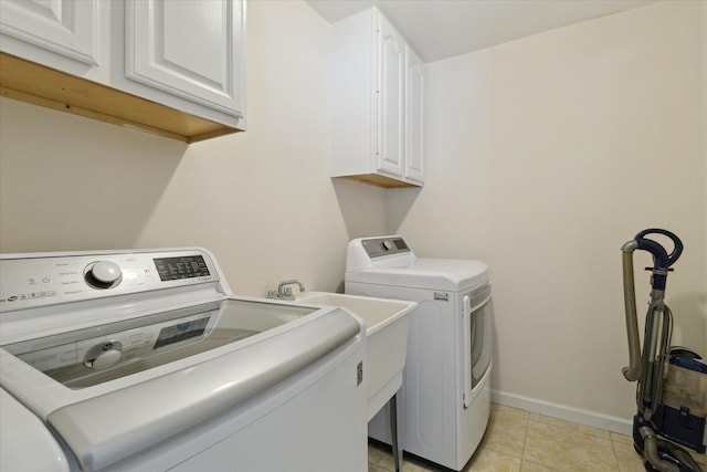 washroom with independent washer and dryer, cabinets, and light tile patterned flooring