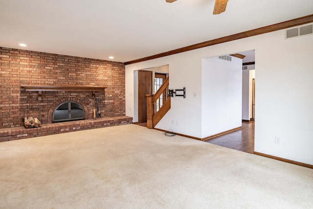 unfurnished living room with a brick fireplace, baseboards, visible vents, and carpet flooring