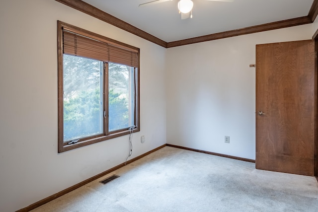 unfurnished room featuring baseboards, crown molding, visible vents, and light colored carpet