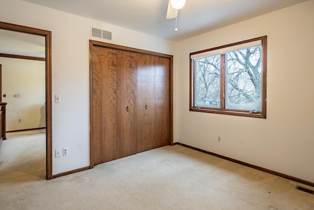 unfurnished bedroom with baseboards, visible vents, a closet, and light colored carpet