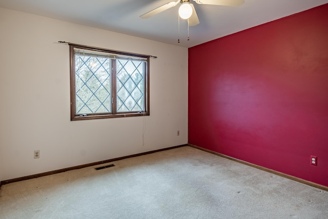 carpeted spare room featuring a ceiling fan, visible vents, and baseboards