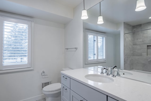 full bathroom featuring toilet, vanity, visible vents, baseboards, and a shower