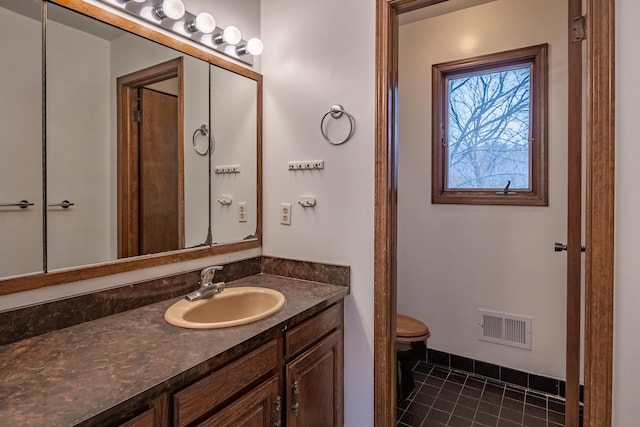 bathroom featuring tile patterned flooring, toilet, vanity, visible vents, and baseboards