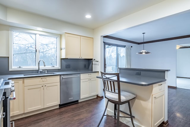 kitchen with dark countertops, appliances with stainless steel finishes, dark wood finished floors, and a sink