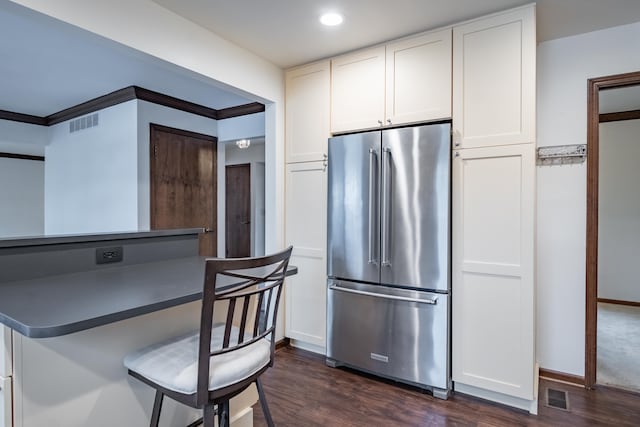 kitchen featuring a breakfast bar area, visible vents, dark wood-type flooring, white cabinets, and high end refrigerator