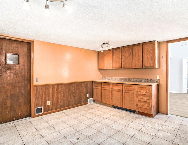 kitchen with track lighting, a textured ceiling, and wood walls