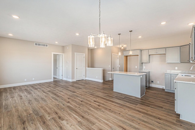 kitchen with gray cabinets, dark hardwood / wood-style floors, sink, hanging light fixtures, and a center island