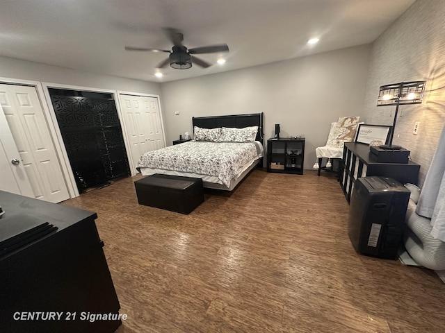 bedroom featuring multiple closets, ceiling fan, and dark hardwood / wood-style floors