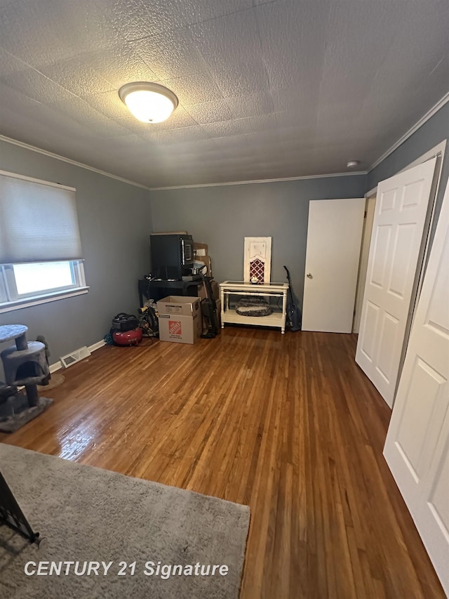 interior space with dark wood-type flooring, ornamental molding, and a textured ceiling