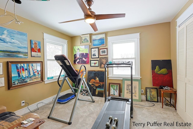 exercise room with ceiling fan, light colored carpet, and plenty of natural light