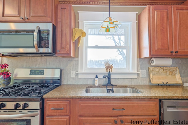 kitchen featuring tasteful backsplash, appliances with stainless steel finishes, decorative light fixtures, and sink