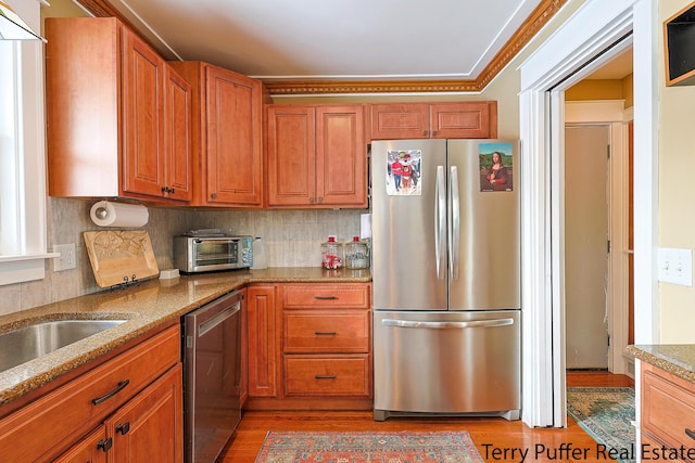 kitchen with stainless steel appliances, light stone countertops, light hardwood / wood-style floors, and backsplash