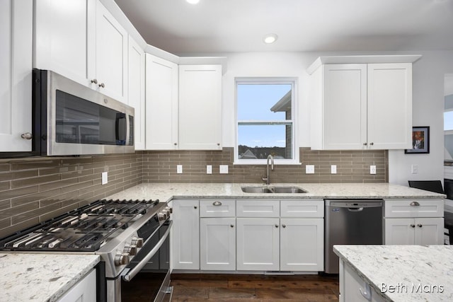 kitchen with a sink, white cabinets, stainless steel appliances, and dark wood-style flooring