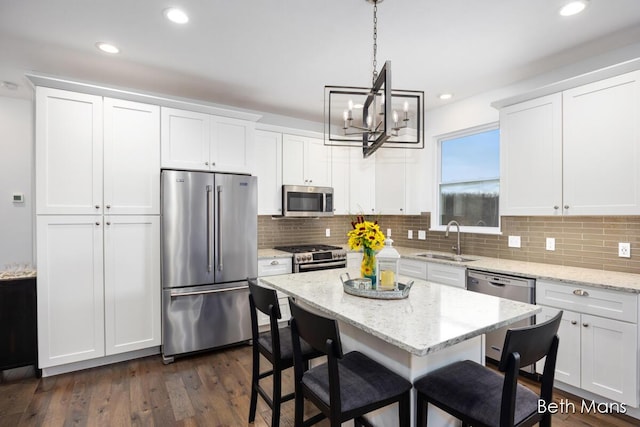 kitchen featuring a sink, a kitchen breakfast bar, a chandelier, stainless steel appliances, and white cabinetry