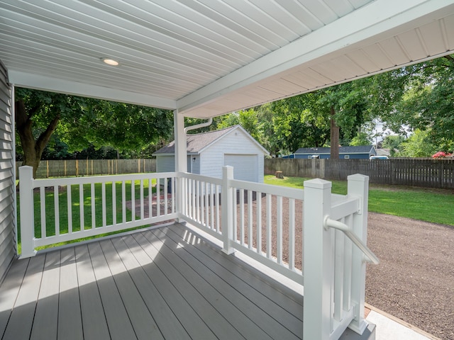 wooden terrace featuring a garage, a lawn, and a storage shed