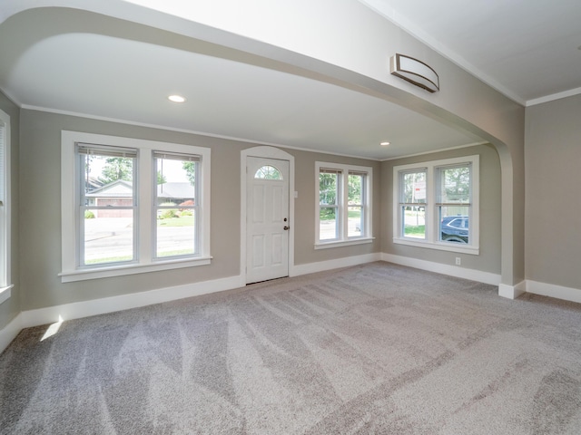 foyer entrance with crown molding and light carpet