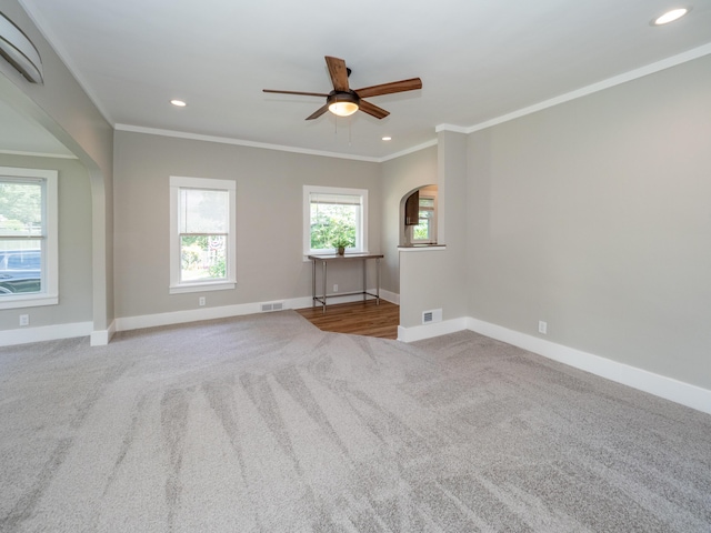 empty room featuring crown molding, a healthy amount of sunlight, and light colored carpet