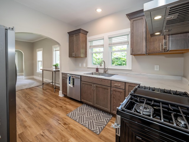 kitchen with stainless steel appliances, sink, a wealth of natural light, and range hood