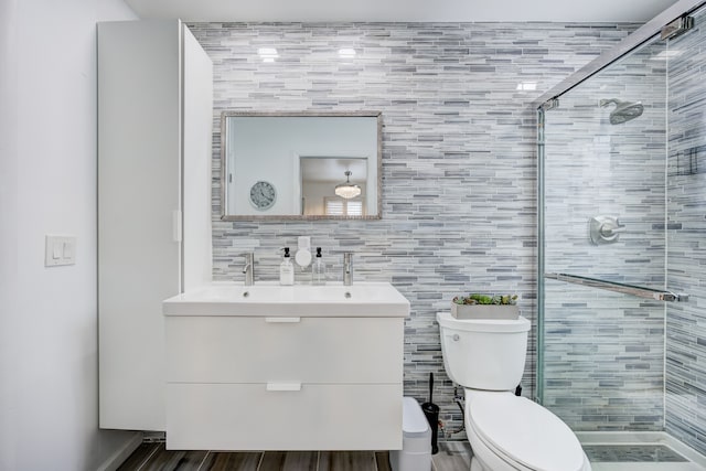 bathroom featuring vanity, a shower with shower door, and toilet