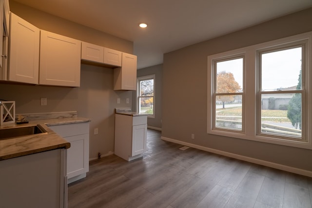 kitchen with white cabinetry, sink, and light wood-type flooring