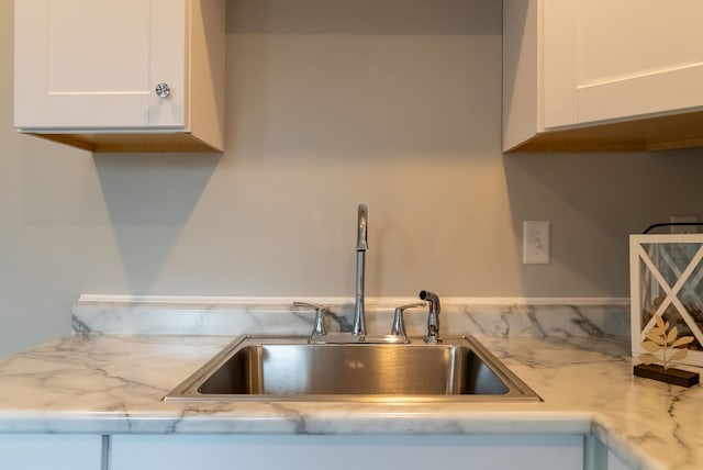 kitchen featuring white cabinetry, sink, and light stone countertops