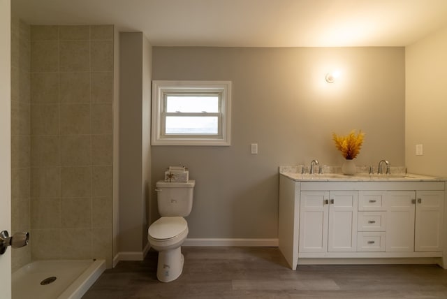 bathroom featuring vanity, wood-type flooring, toilet, and a tile shower