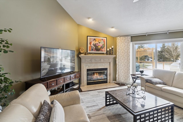 living room featuring lofted ceiling, a high end fireplace, and a textured ceiling