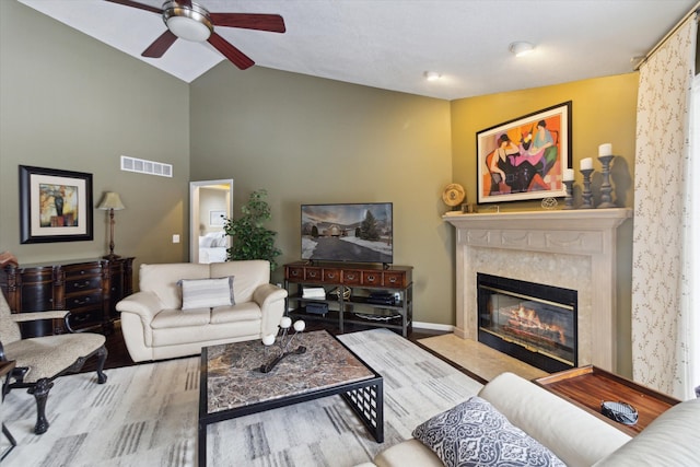 living room with ceiling fan, lofted ceiling, light wood-type flooring, and a high end fireplace