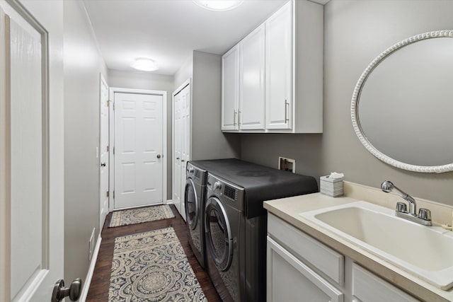 clothes washing area featuring dark hardwood / wood-style flooring, sink, cabinets, and washing machine and clothes dryer