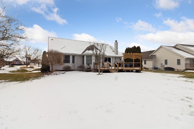 snow covered back of property featuring a wooden deck