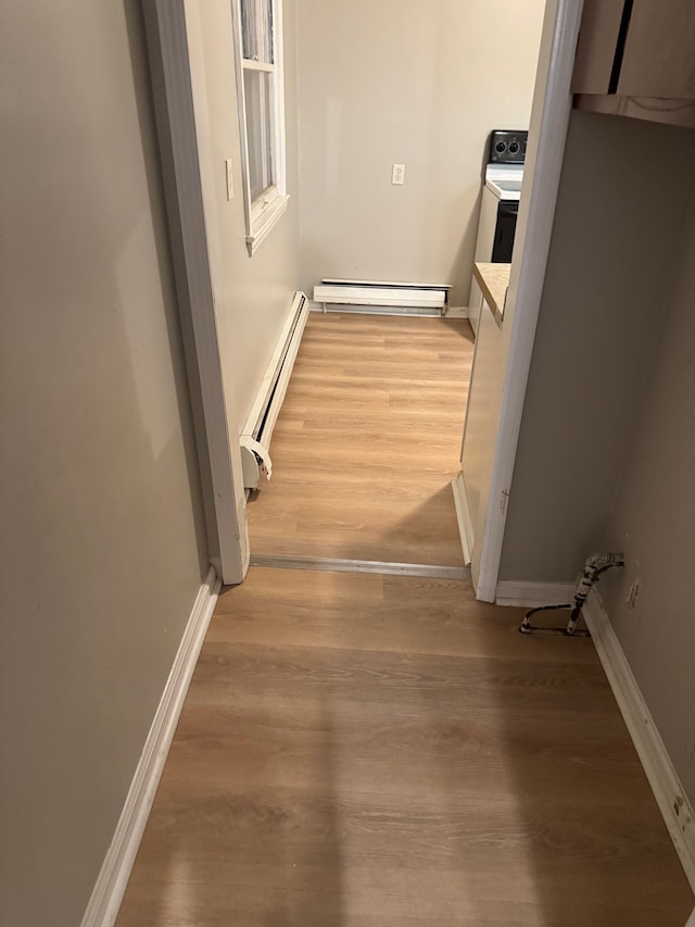 hallway featuring washer / clothes dryer, hardwood / wood-style flooring, and a baseboard heating unit