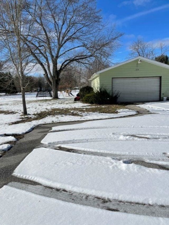 yard covered in snow featuring an outbuilding and a garage