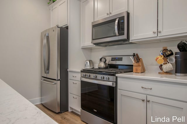 kitchen featuring white cabinetry, light hardwood / wood-style floors, and appliances with stainless steel finishes