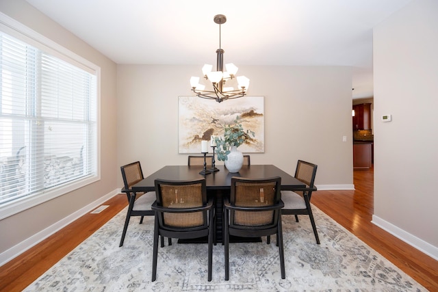 dining area with wood-type flooring and a chandelier