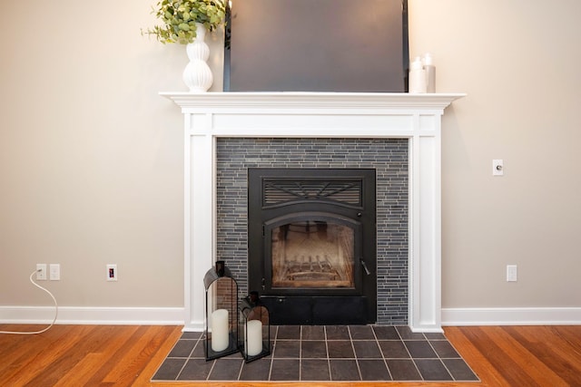 details with hardwood / wood-style flooring and a tiled fireplace