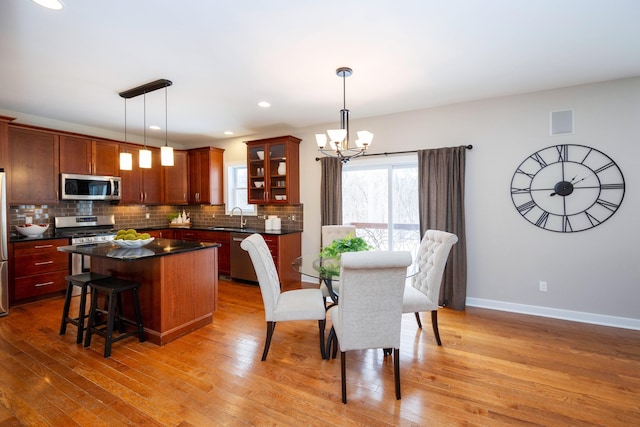 dining room with an inviting chandelier, sink, and light wood-type flooring