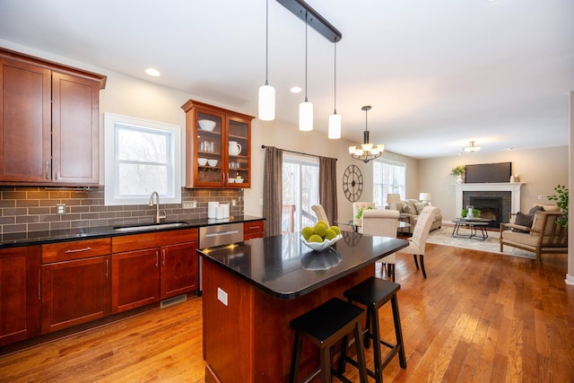 kitchen with sink, backsplash, light hardwood / wood-style floors, a kitchen island, and stainless steel dishwasher