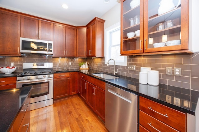 kitchen featuring tasteful backsplash, appliances with stainless steel finishes, sink, and light wood-type flooring