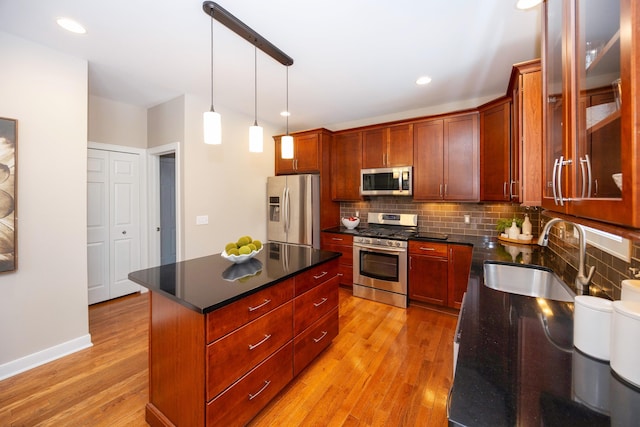 kitchen featuring sink, a center island, pendant lighting, stainless steel appliances, and decorative backsplash