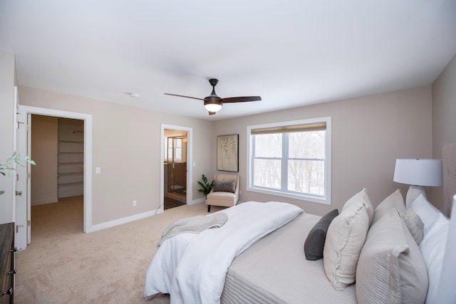 bedroom with ceiling fan, a walk in closet, ensuite bathroom, and light carpet