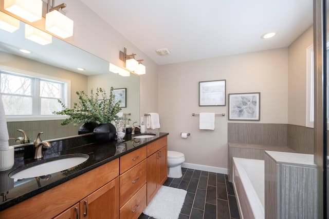 bathroom featuring vanity, a relaxing tiled tub, and toilet