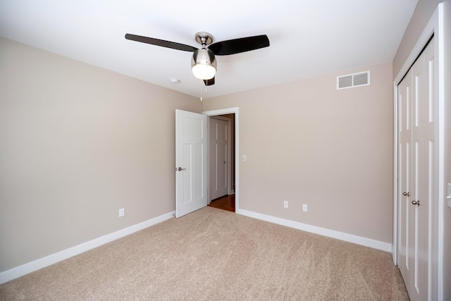 unfurnished bedroom with ceiling fan, a closet, and light carpet