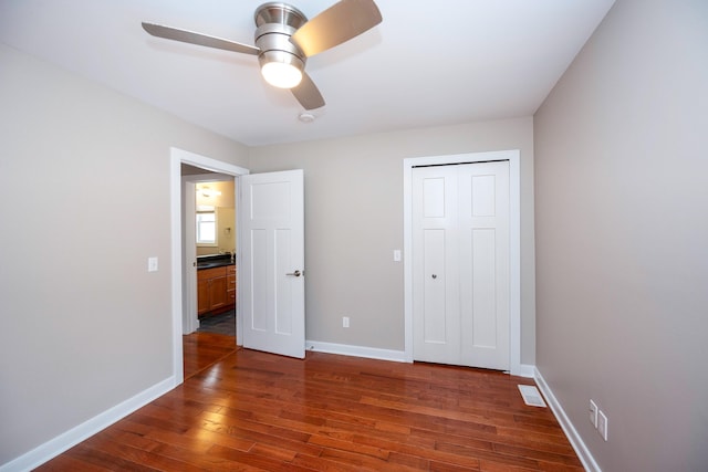 unfurnished bedroom featuring dark wood-type flooring, ceiling fan, and a closet