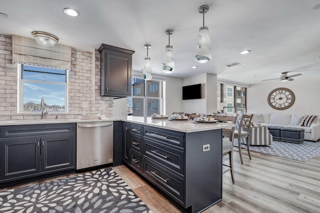 kitchen with a kitchen bar, sink, decorative light fixtures, dishwasher, and kitchen peninsula