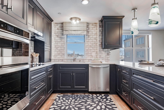 kitchen featuring pendant lighting, stainless steel appliances, sink, and light wood-type flooring