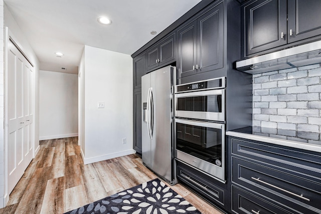 kitchen with stainless steel appliances, light hardwood / wood-style floors, and extractor fan